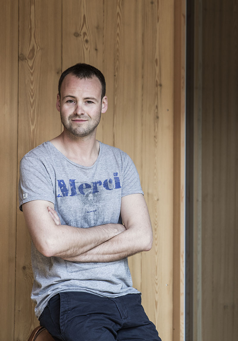 Portraitfoto Stefan stehend von Holzwand
